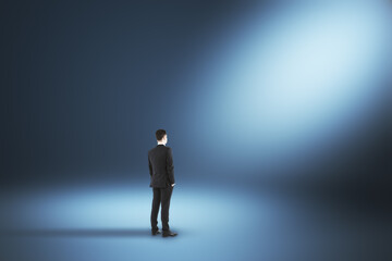 Fototapeta premium Businessman in suit standing in illuminated interior with spotlight.