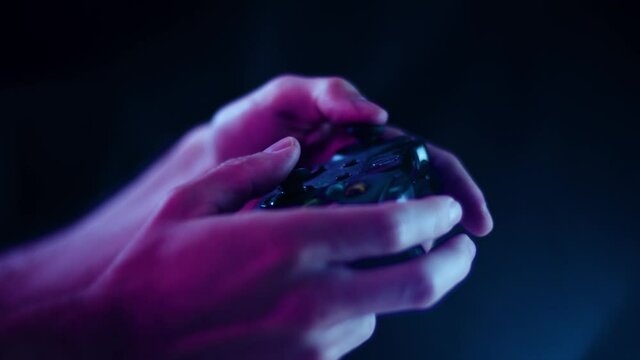 Playing video games in a darkened room with a black background close up on a controller joystick playing quikly blue lens flare
