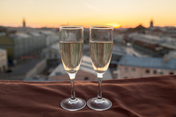 Two glasses of champagne on the background of city roofs at sunset