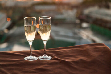 Two glasses of champagne on the background of city roofs at sunset
