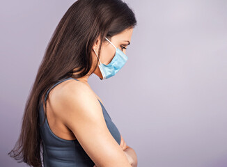 Female in respiratory blue mask. Serious woman looking down. Cold, flu, virus, tonsillitis, respiratory disease, quarantine, epidemic concept portrait. Beautiful caucasian woman with empty space.