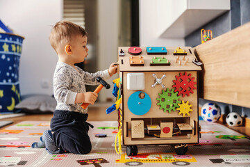 Adorable toddler playing interactive games for good development at home. - obrazy, fototapety, plakaty