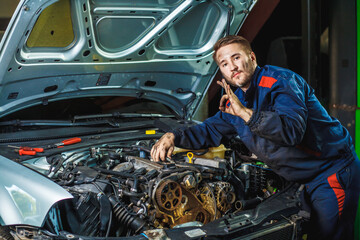 Close up hands of unrecognizable mechanic doing car service and maintenance. Mechanic working in...