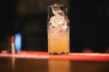 Beautiful row of different colored alcohol cocktails on a party, martini, vodka, and others on decorated catering bouquet table on open air event with bartender in the background