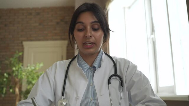Indian doctor talking to camera making online video call consulting patient. Female gp looking at webcamera speaking in conference chat. Webcam face view. Telemedicine in India, telehealth consultancy