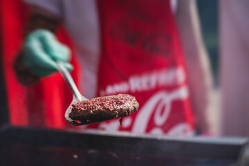 Process of cooking classic burgers with beef on open-air, view of chef hands in  gloves with variety of fillings and ingredients on wooden desk and stove