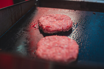 Process of cooking classic burgers with beef on open-air, view of chef hands in  gloves with variety of fillings and ingredients on wooden desk and stove