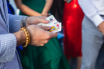 Magician showing card tricks focus in front of guests on party event wedding celebration, juggler performing show