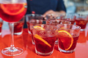 View of alcohol setting on catering banquet table, row line of red colored aperitif alcohol cocktails on a party, negroni and spritz, vodka, and others on decorated catering bouquet table event