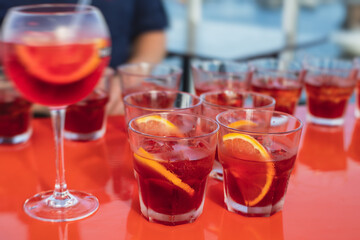 View of alcohol setting on catering banquet table, row line of red colored aperitif alcohol cocktails on a party, negroni and spritz, vodka, and others on decorated catering bouquet table event