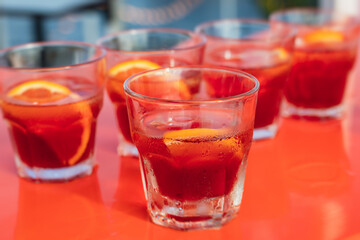 View of alcohol setting on catering banquet table, row line of red colored aperitif alcohol cocktails on a party, negroni and spritz, vodka, and others on decorated catering bouquet table event