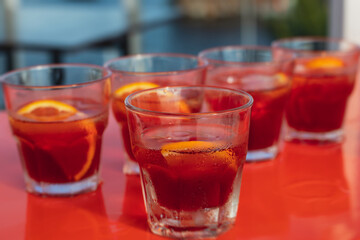View of alcohol setting on catering banquet table, row line of red colored aperitif alcohol cocktails on a party, negroni and spritz, vodka, and others on decorated catering bouquet table event