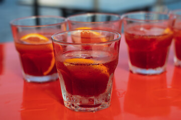 View of alcohol setting on catering banquet table, row line of red colored aperitif alcohol cocktails on a party, negroni and spritz, vodka, and others on decorated catering bouquet table event