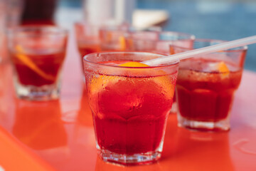 View of alcohol setting on catering banquet table, row line of red colored aperitif alcohol cocktails on a party, negroni and spritz, vodka, and others on decorated catering bouquet table event