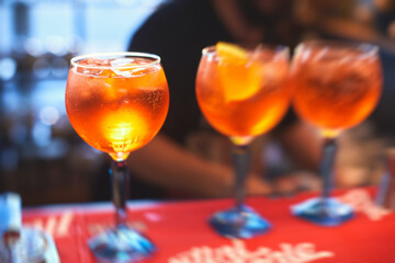 Row line of red colored negroni and spritz aperitif alcohol cocktails on a party of alcohol setting on catering banquet table, vodka, and others on decorated catering table event with bartender