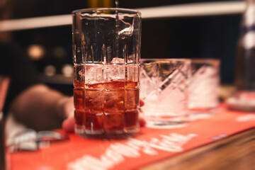 Row line of red colored negroni and spritz aperitif alcohol cocktails on a party of alcohol setting on catering banquet table, vodka, and others on decorated catering table event with bartender