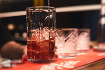 Row line of red colored negroni and spritz aperitif alcohol cocktails on a party of alcohol setting on catering banquet table, vodka, and others on decorated catering table event with bartender