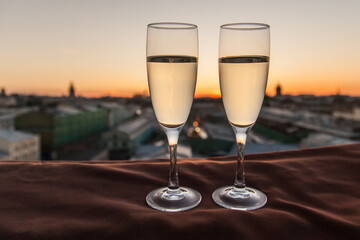 Two glasses of champagne on the background of city roofs at sunset