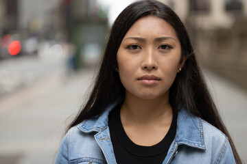 Young Asian woman  sad serious face portrait in city