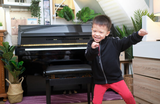 Cute Happy Smiling Little Asian Kid Boy Having Fun Dancing To Music Indoors In Living Room At Home, Active Leisure And Lifestyle Concept, Photo In Real Life Interior