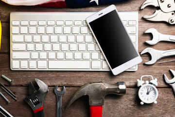 Happy USA Labor day, different kind wrenches with American flag and smartphone blank screen on keyboard. First Monday in September creation of labor movement and dedicated to social of American worker