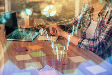 Double exposure of businesswoman hands typing on computer and forex graph hologram drawing. Financial analysis concept.