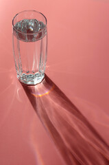 still life. Glittering glasses of water on pink table background in sunlight. Refreshment concept.
