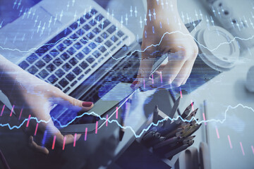 Double exposure of businesswoman hands typing on computer and financial graph hologram drawing. Stock market analysis concept.
