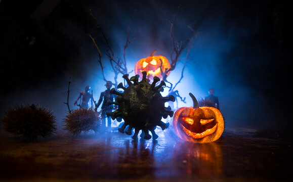 Halloween during Corona virus global pandemic concept. Glowing pumpkins and Covid novel on dark with thematic spooky decorations. Halloween pumpkin on foggy backlight.
