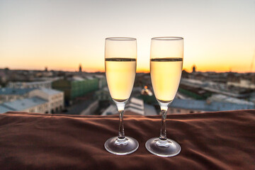 Two glasses of champagne on the background of city roofs at sunset