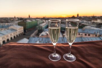 Two glasses of champagne on the background of city roofs at sunset