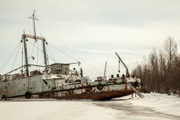Abandoned white ship frozen in ice near lighthouse