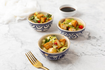 Tofu and Vegetables Stir Fry in Blue and White Bowls on White Background