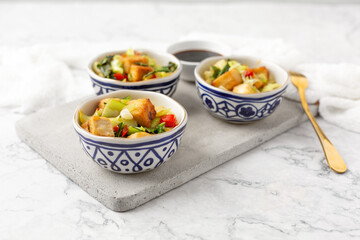 Fototapeta na wymiar Tofu and Vegetables Stir Fry in Blue and White Bowls on White Background