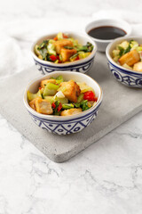 Tofu and Vegetables Stir Fry in Blue and White Bowls on White Background