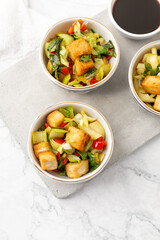 Tofu and Vegetables Stir Fry in Blue and White Bowls on White Background