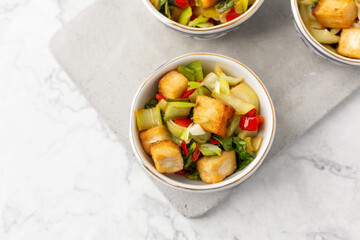 Tofu and Vegetables Stir Fry in Blue and White Bowls on White Background