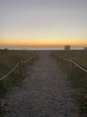 Fototapeta na wymiar Sandy walkway leading to tricolor beach sunset