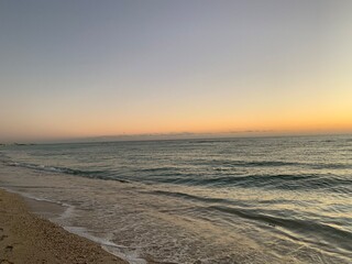 Fototapeta na wymiar Vibrant sunset over calm sandy beach shoreline