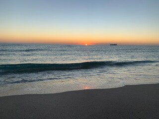 Landscape view of vibrant sunset over calm sandy beach shoreline