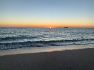 Landscape view of vibrant sunset over calm sandy beach shoreline