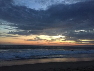 Seascape view of cloudy pastel sunset over calm beach waters