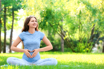 Young pregnant woman practicing yoga outdoors