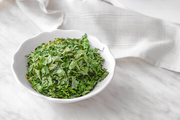 Bowl with dry parsley on table