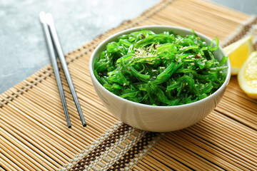 Bowl with tasty seaweed salad on table