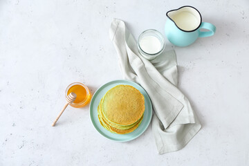 Obraz na płótnie Canvas Plate with tasty green pancakes, milk and honey on white background