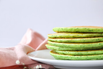 Plate with tasty green pancakes on table