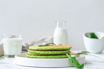 Plate with tasty green pancakes on table