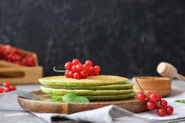 Plate with tasty green pancakes and berries on table