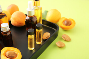 Bottles of apricot essential oil on color background